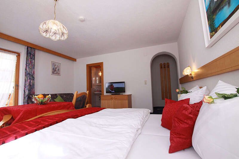 Double room with seating and TV in La Fontana in Kappl